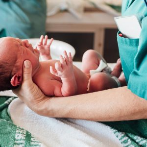 A doctor holding and treating a newborn baby.