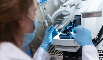 A researcher uses a laboratory device with a magnifying lens.